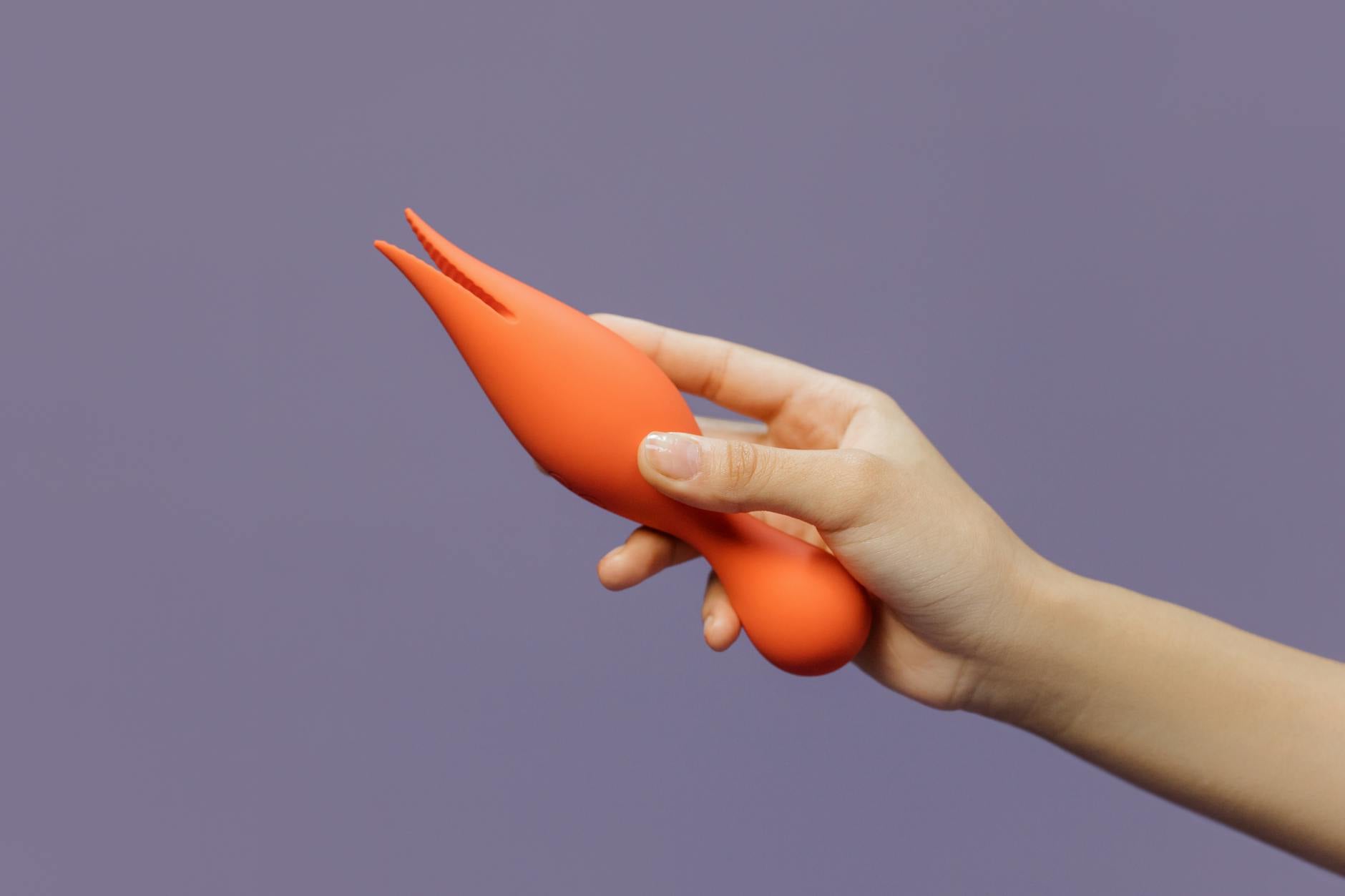 Close-up of hands holding a sleek blue vibrator against a purple background, representing intimate shared moments
